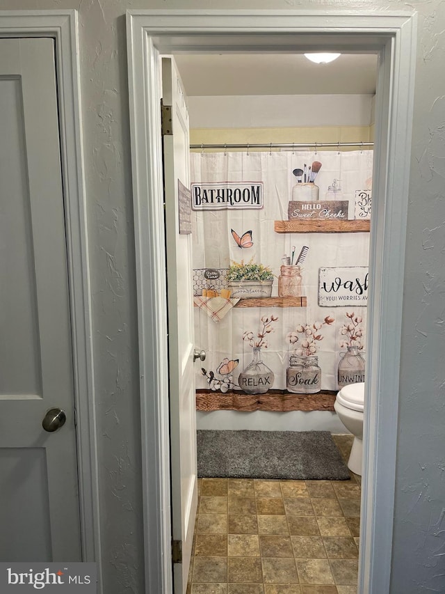 bathroom with curtained shower and toilet