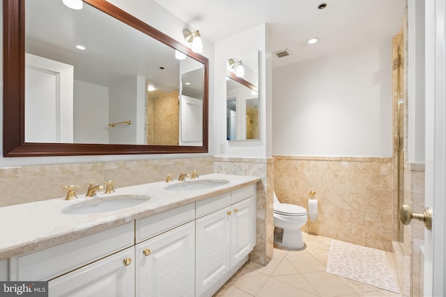 bathroom with tile patterned floors, vanity, toilet, and tile walls