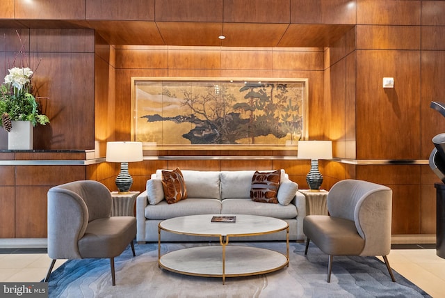 living area with wooden walls and light tile patterned floors