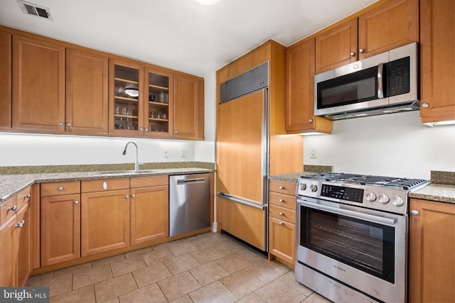 kitchen featuring light stone countertops, sink, and high end appliances