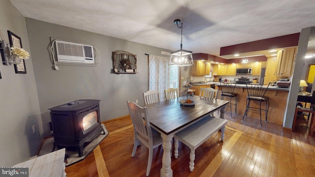 dining area with light wood-type flooring, a wood stove, and a wall mounted AC