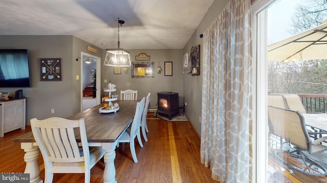 dining space with wood-type flooring and a wood stove