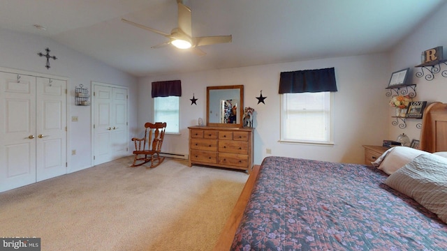 carpeted bedroom with ceiling fan, multiple closets, a baseboard radiator, and vaulted ceiling