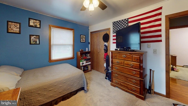 bedroom featuring ceiling fan, a closet, and light colored carpet