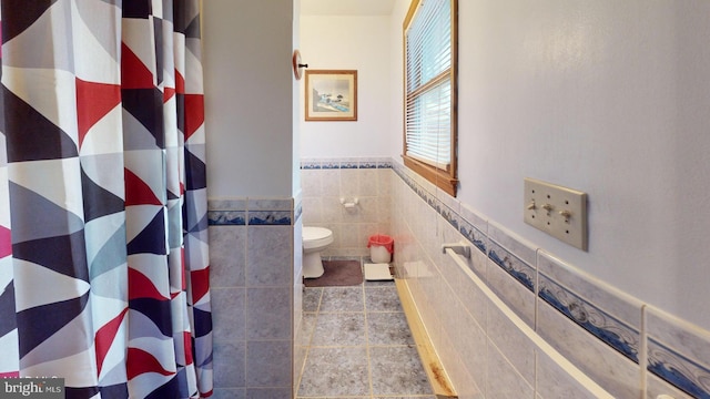 bathroom with toilet, tile walls, and curtained shower