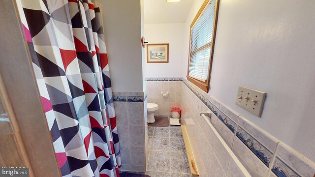 bathroom featuring toilet, tile walls, and walk in shower