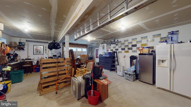 garage featuring a workshop area, stainless steel fridge, and white fridge with ice dispenser