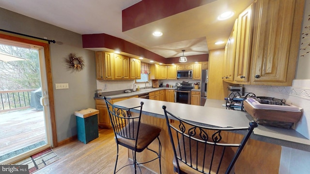 kitchen with a kitchen breakfast bar, light wood-type flooring, kitchen peninsula, and stainless steel appliances