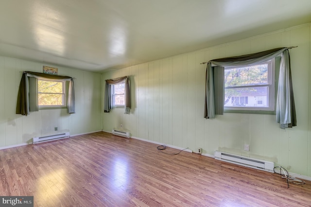 empty room with a baseboard radiator, light hardwood / wood-style flooring, and plenty of natural light