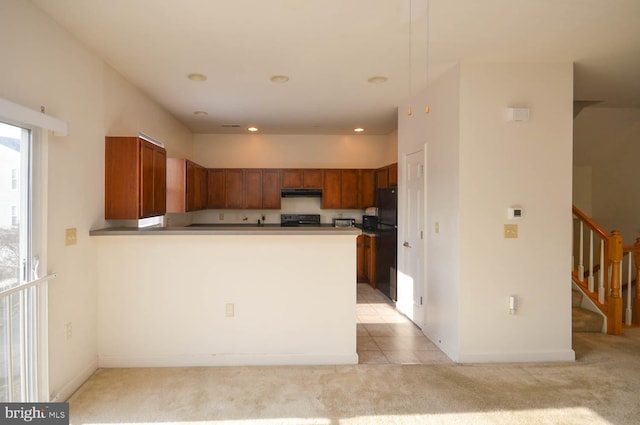 kitchen featuring kitchen peninsula, black refrigerator, light colored carpet, and range