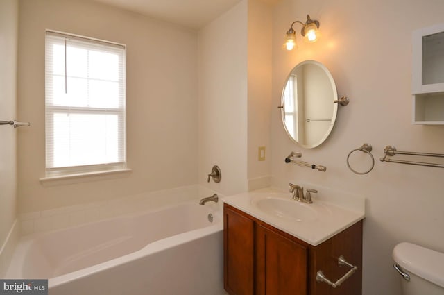 bathroom featuring a washtub, vanity, a healthy amount of sunlight, and toilet