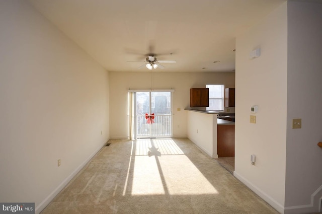 kitchen with ceiling fan and light colored carpet