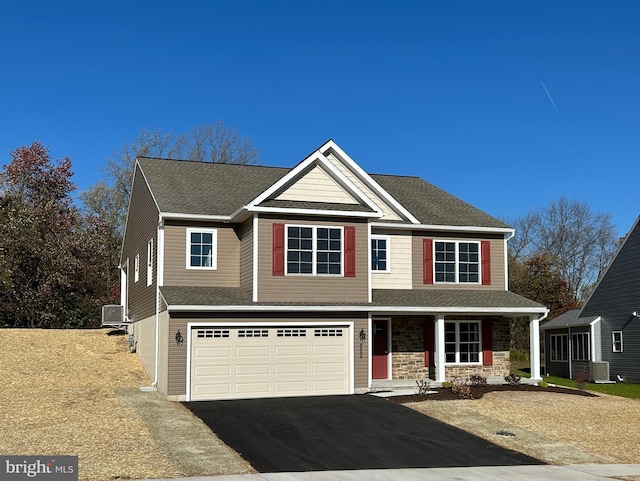 view of front of house with covered porch, a garage, and central AC unit