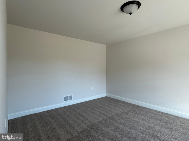 spare room with dark carpet