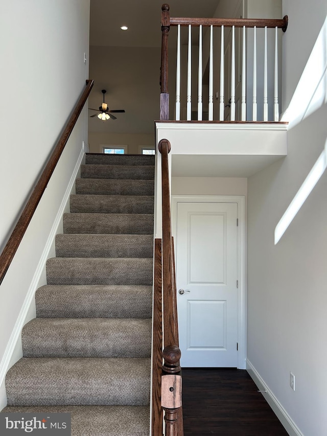 stairway with ceiling fan and wood-type flooring