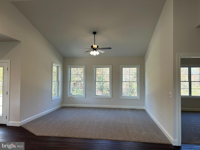 unfurnished room with lofted ceiling, plenty of natural light, dark wood-type flooring, and ceiling fan