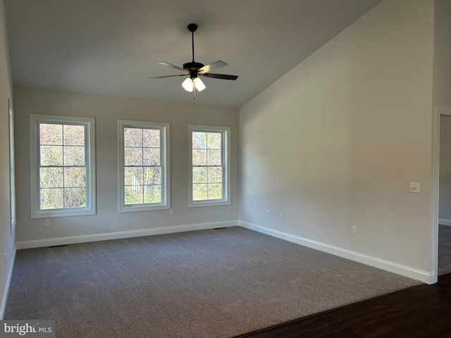 spare room with plenty of natural light, ceiling fan, dark wood-type flooring, and vaulted ceiling