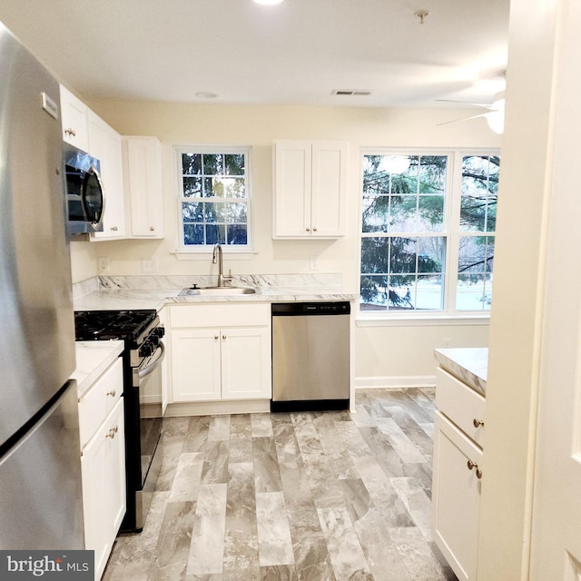 kitchen featuring white cabinets, ceiling fan, sink, and stainless steel appliances