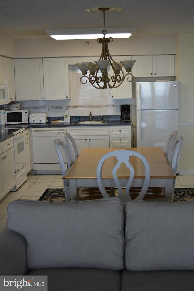 kitchen featuring decorative backsplash, sink, white cabinets, and white appliances