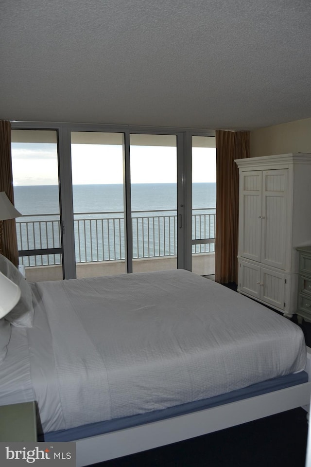 unfurnished bedroom featuring access to exterior, a water view, and a textured ceiling