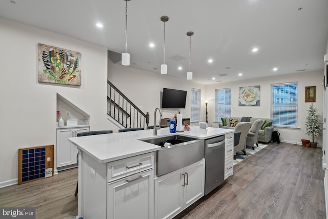 kitchen featuring dishwasher, a kitchen island with sink, hanging light fixtures, light hardwood / wood-style floors, and white cabinetry