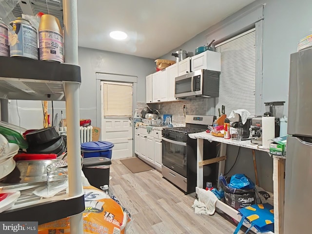 kitchen with white cabinetry, backsplash, pendant lighting, appliances with stainless steel finishes, and light wood-type flooring