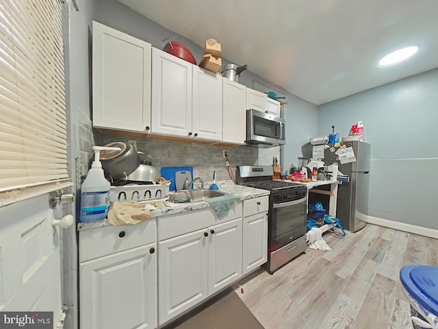 kitchen with sink, decorative backsplash, light hardwood / wood-style floors, white cabinetry, and stainless steel appliances