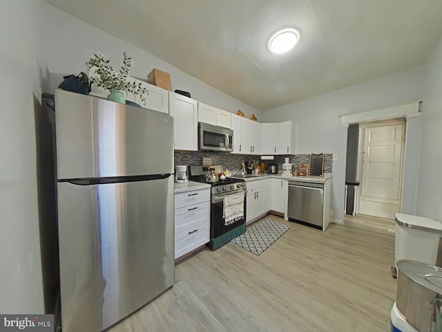 kitchen featuring white cabinetry, sink, stainless steel appliances, tasteful backsplash, and light hardwood / wood-style flooring