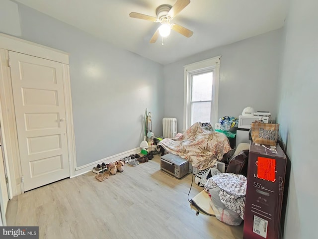 miscellaneous room featuring radiator, ceiling fan, and light hardwood / wood-style flooring