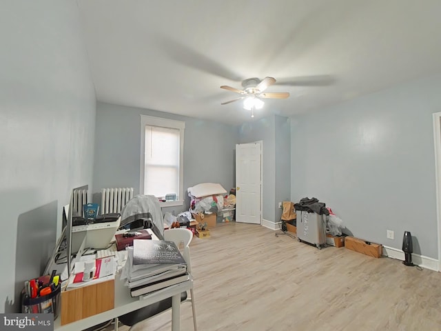 misc room featuring ceiling fan, light hardwood / wood-style floors, and radiator heating unit