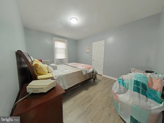 bedroom featuring radiator heating unit, light wood-type flooring, and cooling unit