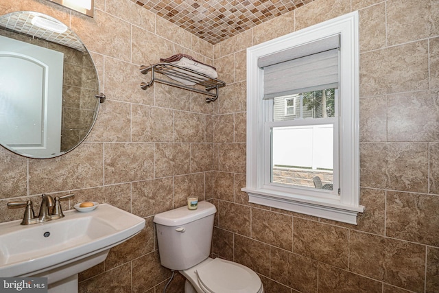 bathroom with toilet, tile walls, and sink