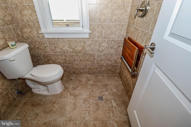 bathroom featuring toilet and tile walls