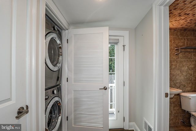 laundry area with tile walls and stacked washer and clothes dryer