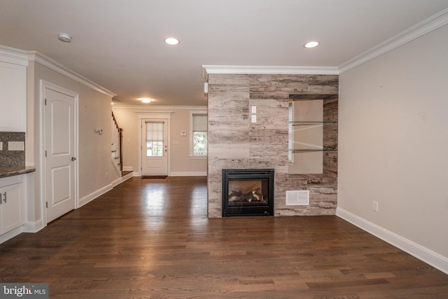 unfurnished living room featuring crown molding, dark wood-type flooring, and a tiled fireplace