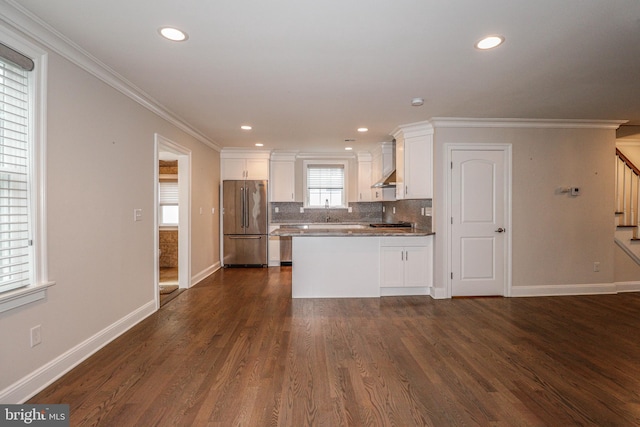 kitchen featuring white cabinetry, wall chimney range hood, dark hardwood / wood-style floors, stainless steel fridge, and ornamental molding