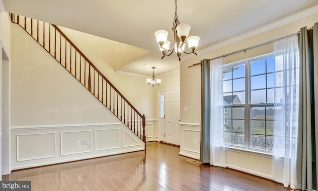 entrance foyer featuring an inviting chandelier, hardwood / wood-style flooring, and crown molding