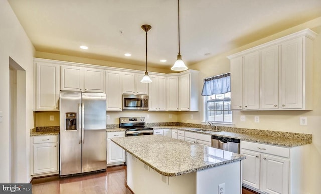 kitchen featuring stainless steel appliances, sink, white cabinetry, a kitchen island, and pendant lighting