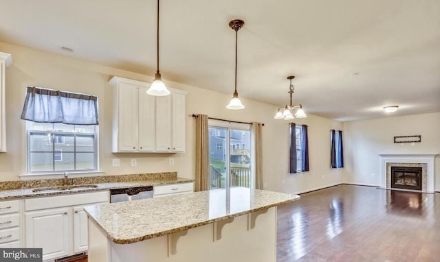 kitchen featuring white cabinets, a breakfast bar area, hanging light fixtures, sink, and stainless steel dishwasher