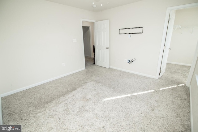 unfurnished bedroom featuring a walk in closet, a closet, and light carpet