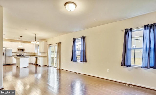 unfurnished living room featuring a notable chandelier and hardwood / wood-style floors