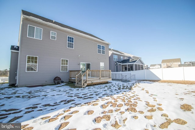 snow covered back of property with a wooden deck