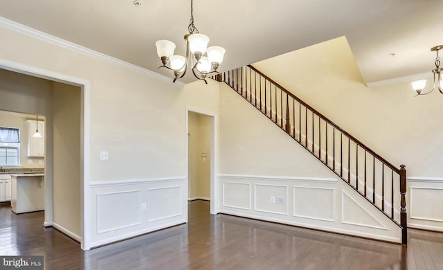 stairway with an inviting chandelier, crown molding, and wood-type flooring