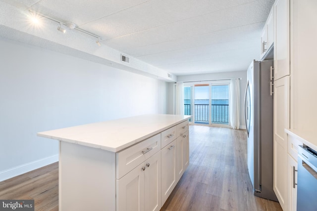 kitchen with dishwashing machine, white cabinetry, light wood-style flooring, and freestanding refrigerator