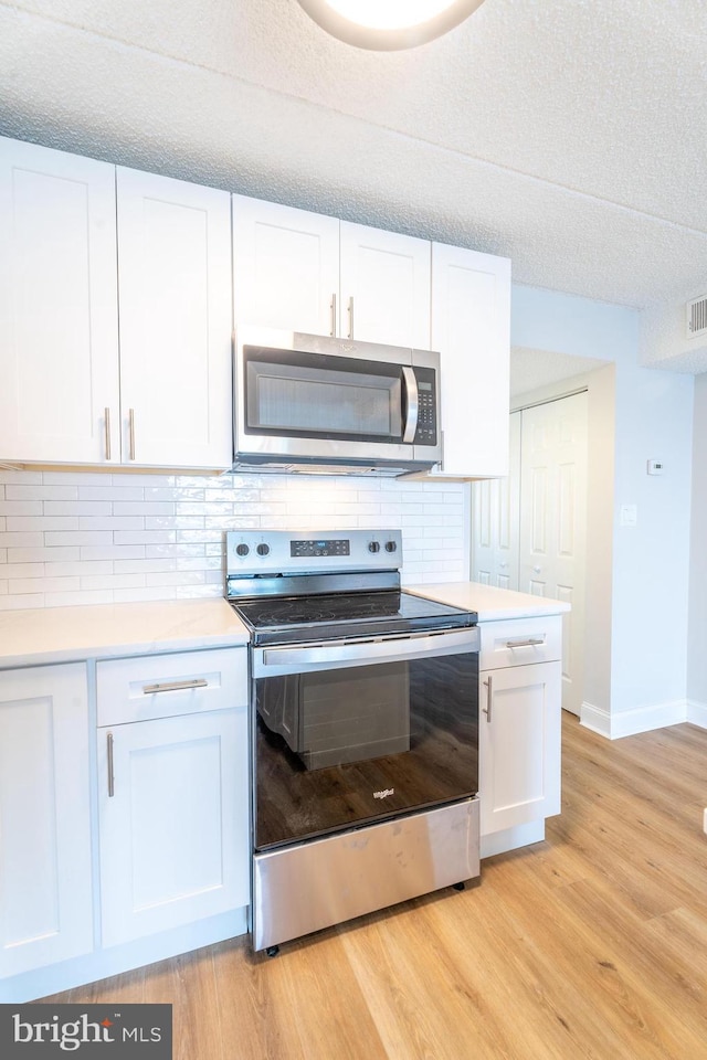 kitchen featuring decorative backsplash, white cabinetry, and appliances with stainless steel finishes