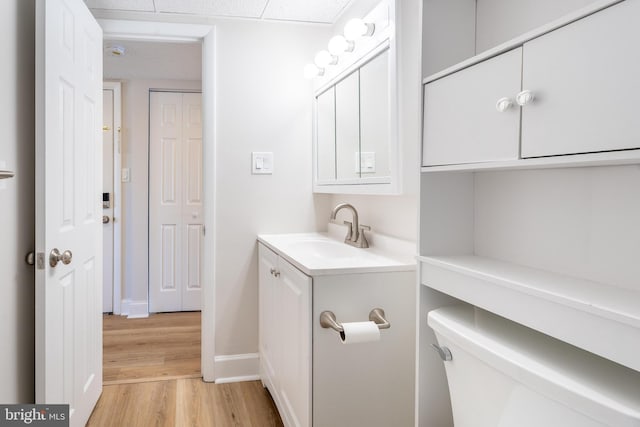 bathroom featuring baseboards, wood finished floors, and vanity