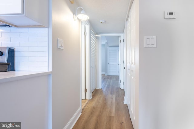 hallway with light wood finished floors and baseboards