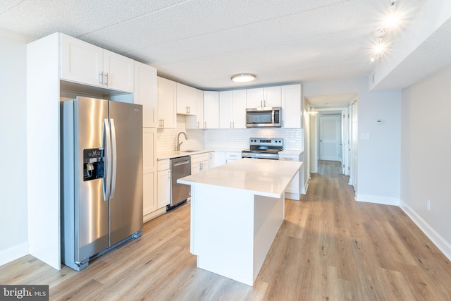 kitchen featuring a kitchen island, white cabinetry, stainless steel appliances, and light hardwood / wood-style flooring