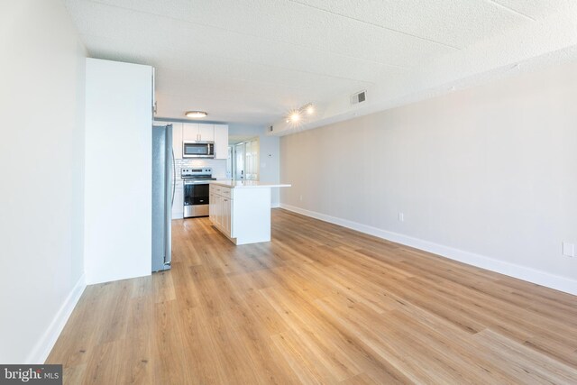 kitchen featuring light wood finished floors, visible vents, backsplash, light countertops, and appliances with stainless steel finishes