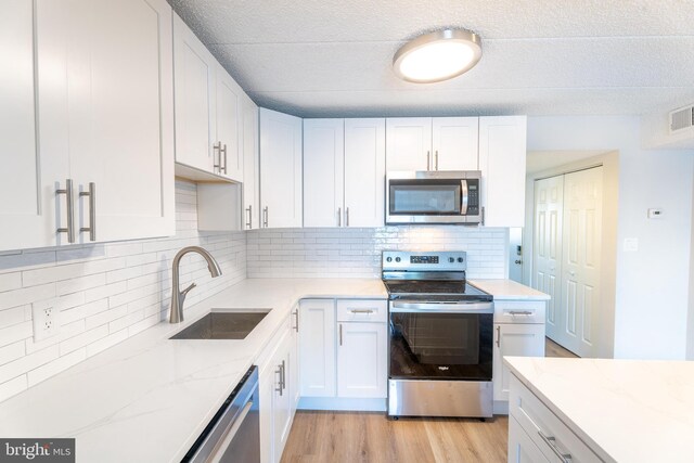 kitchen with white cabinets, stainless steel appliances, light hardwood / wood-style flooring, and sink